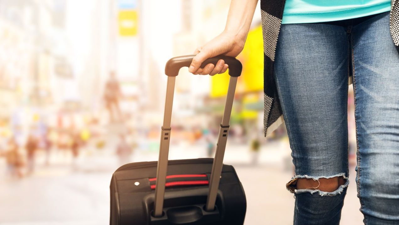 A woman is pulling a suitcase down a street.