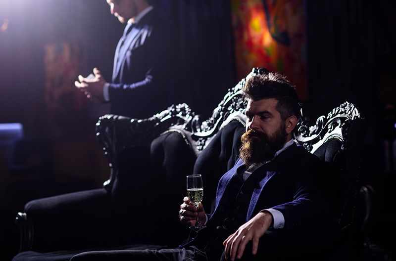 a man in a suit is sitting on a couch holding a glass of champagne .