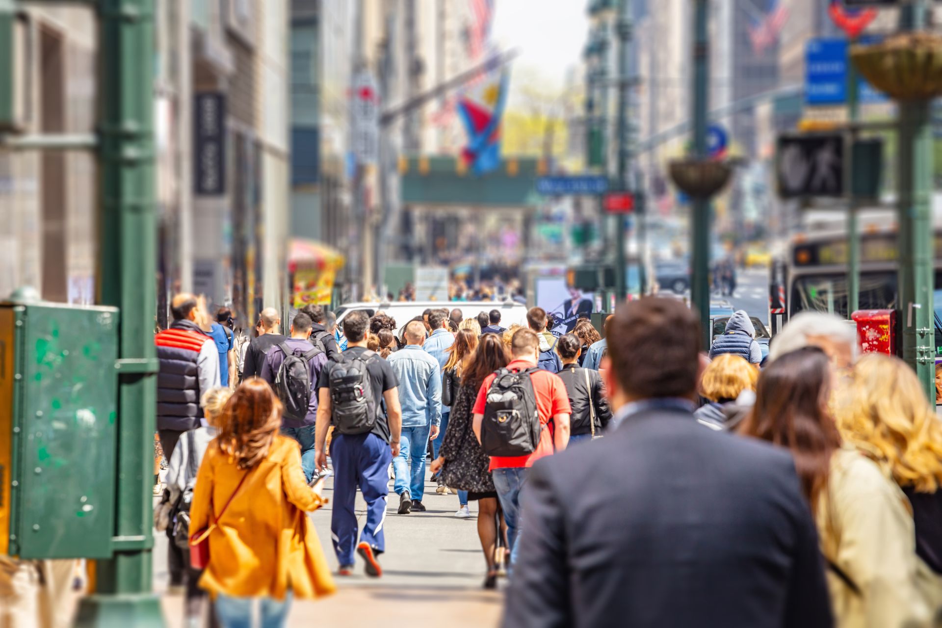 A large group of people are walking down a busy city street.