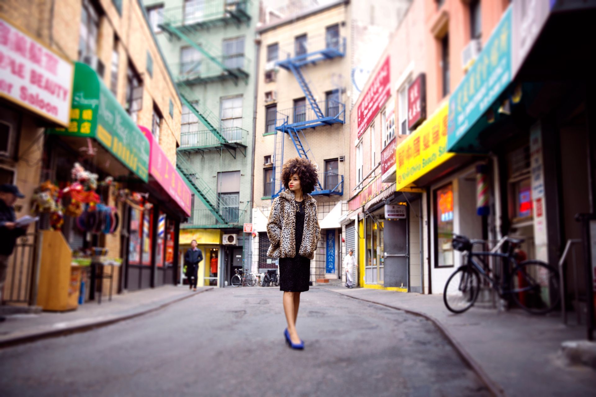 A woman with an afro is walking down a city street