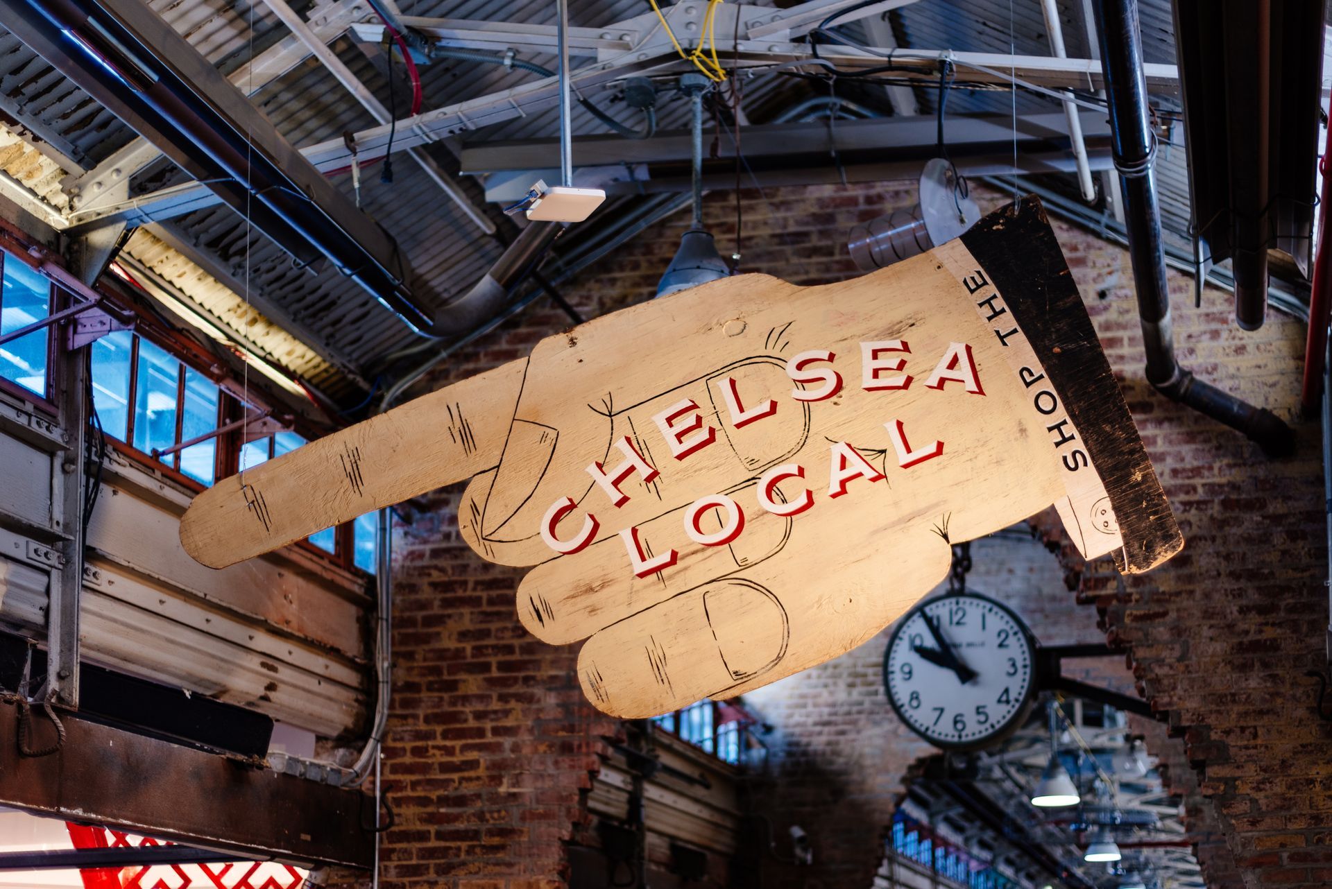 A sign that says chelsea local is hanging from the ceiling