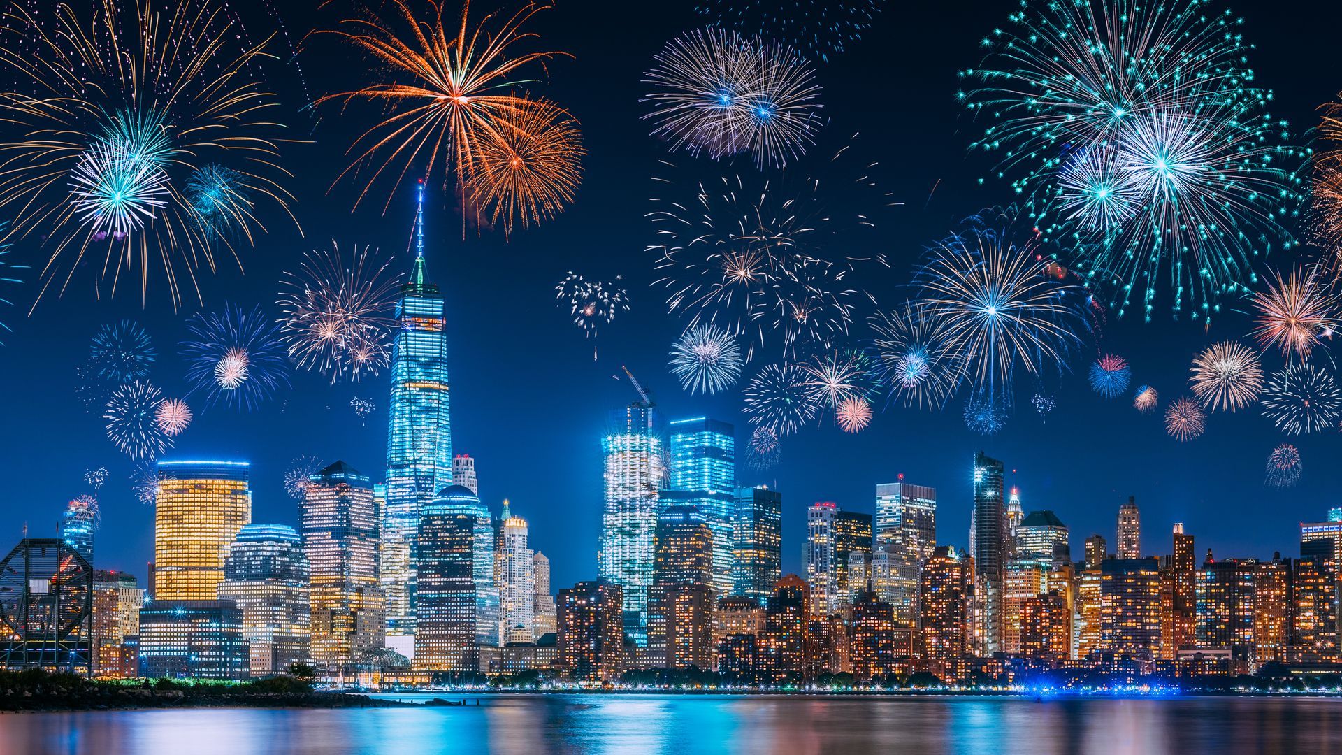 Fireworks explode over the New York City skyline at night.