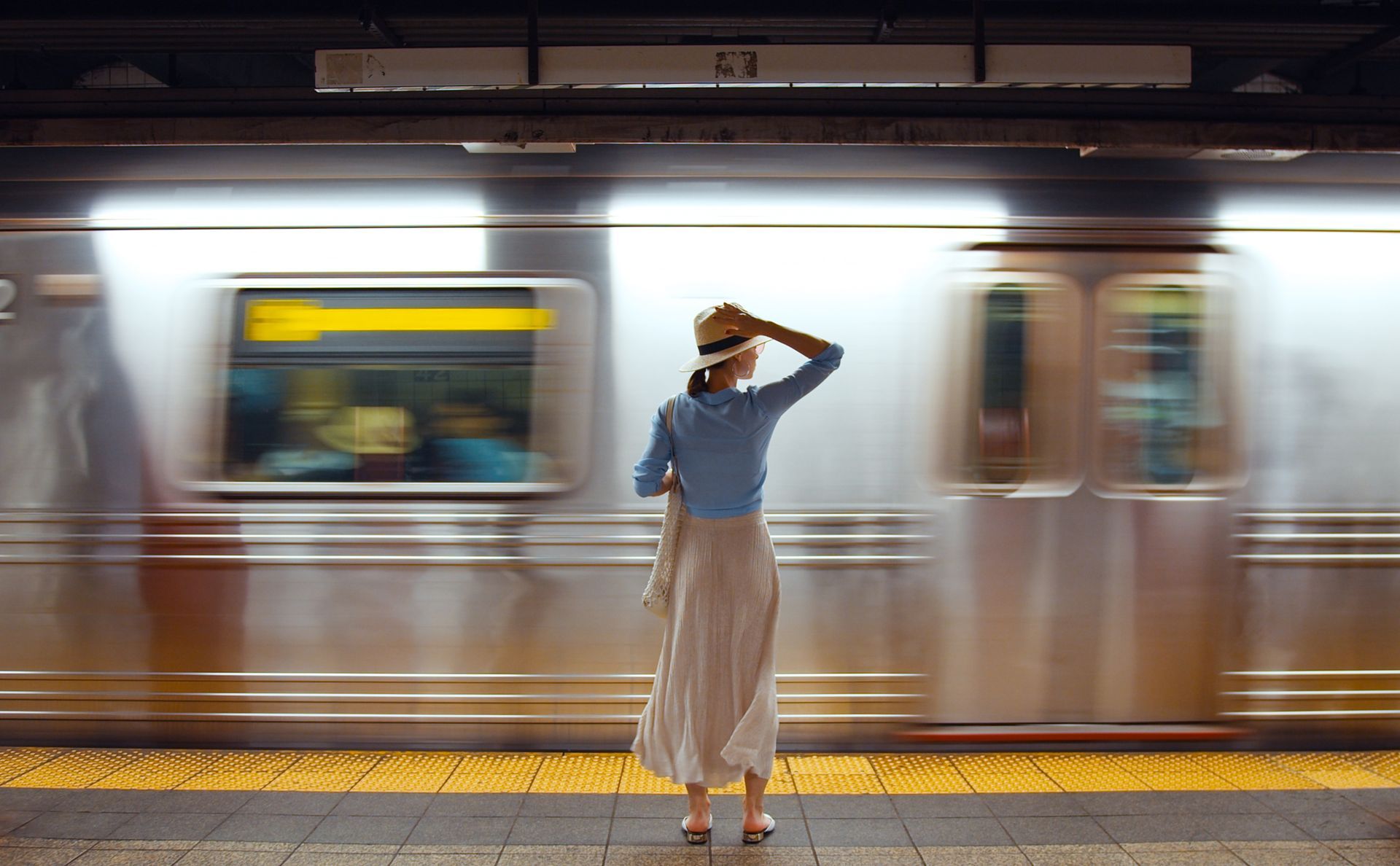 A woman is standing in front of a train at a subway station