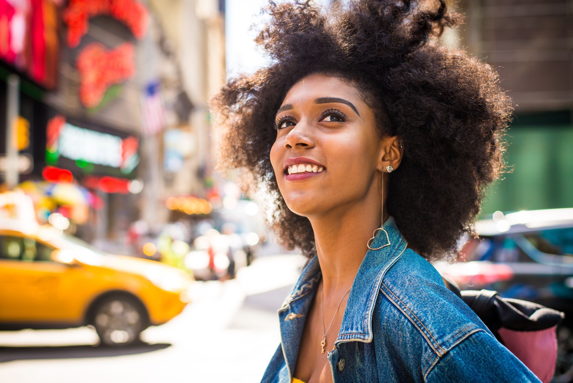 A woman with an afro is walking down a city street.