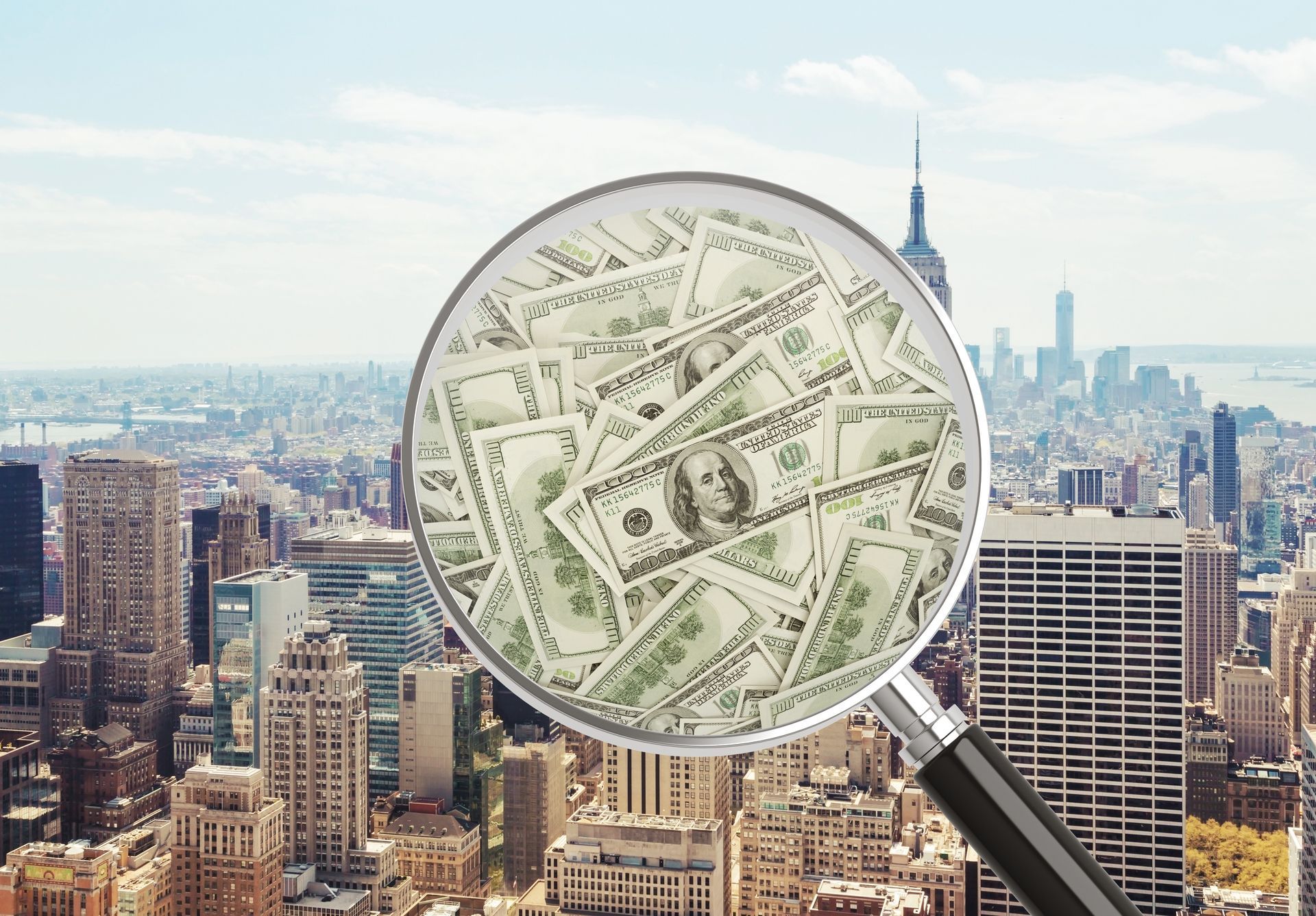 A magnifying glass is looking at a pile of money in a city.