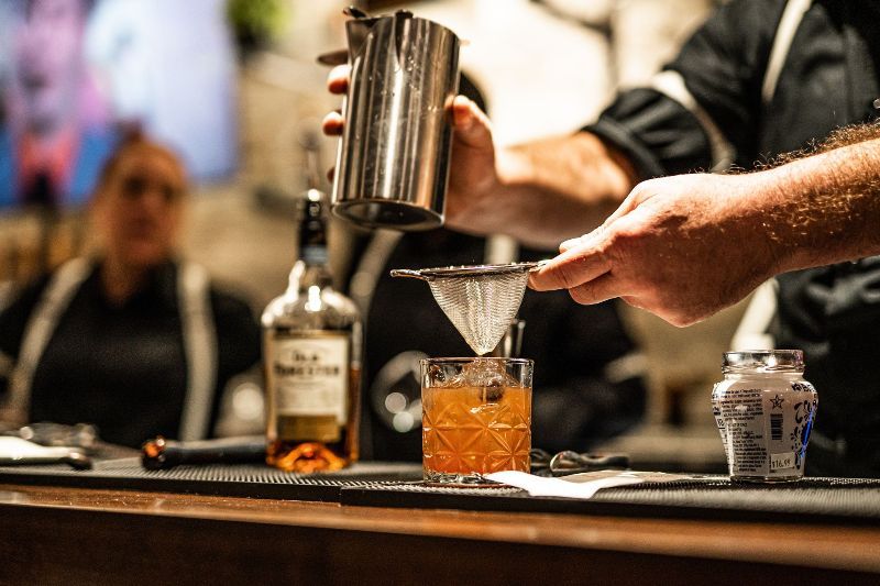 a bartender is pouring a drink into a glass .