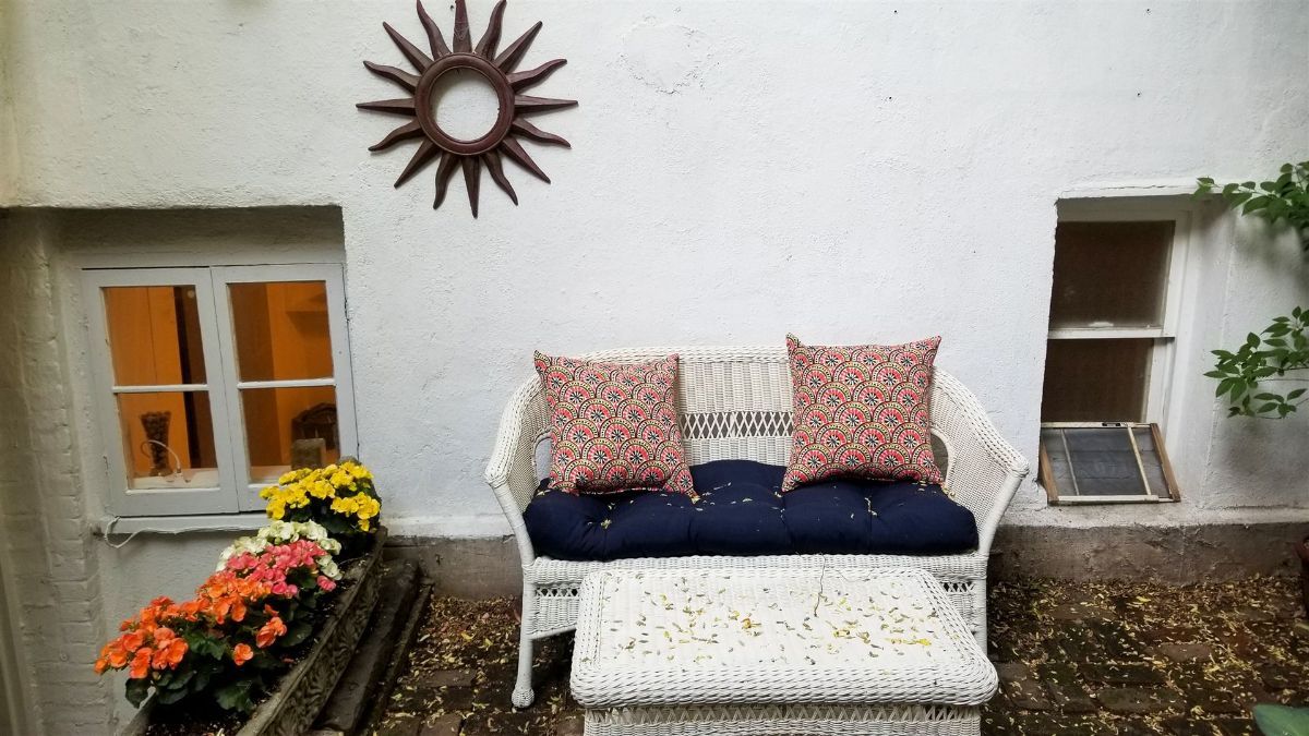 a white wicker couch is sitting in front of a white wall .