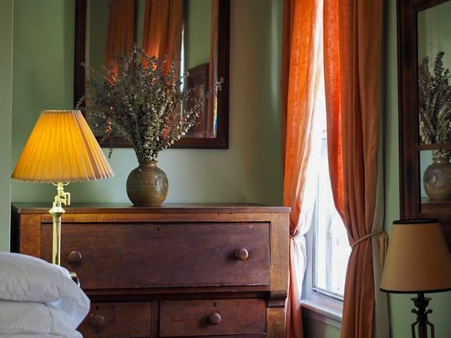 a bedroom with a dresser a lamp and a mirror