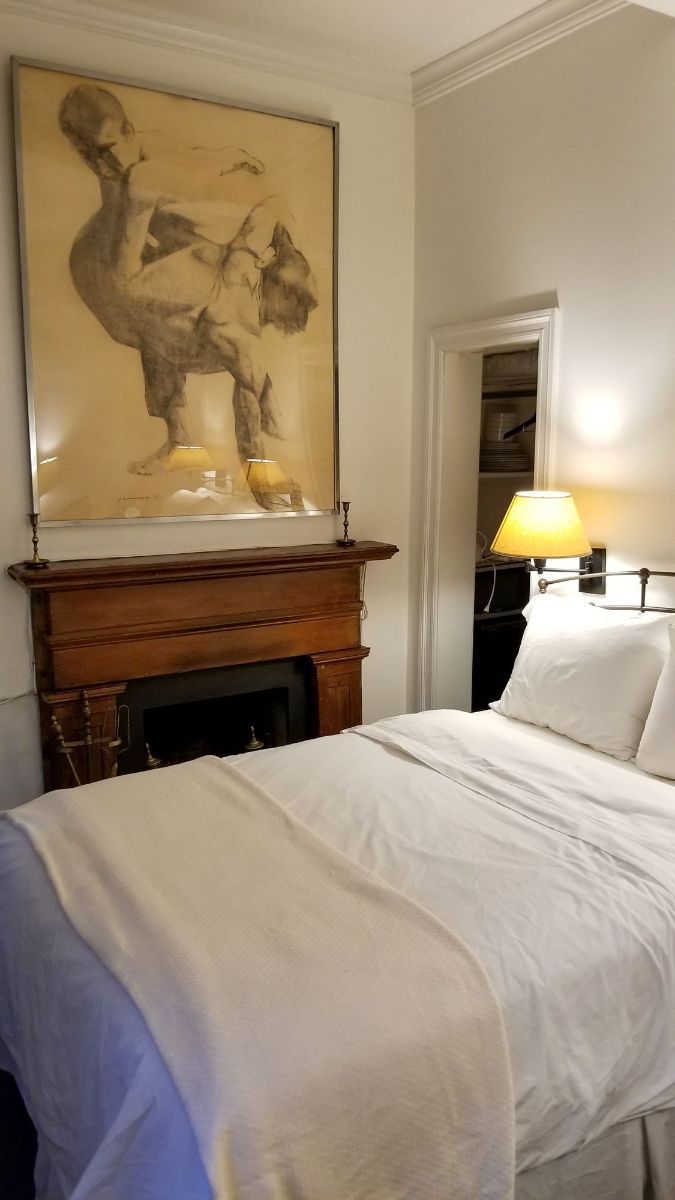 a bedroom with a bed , fireplace and painting on the wall .