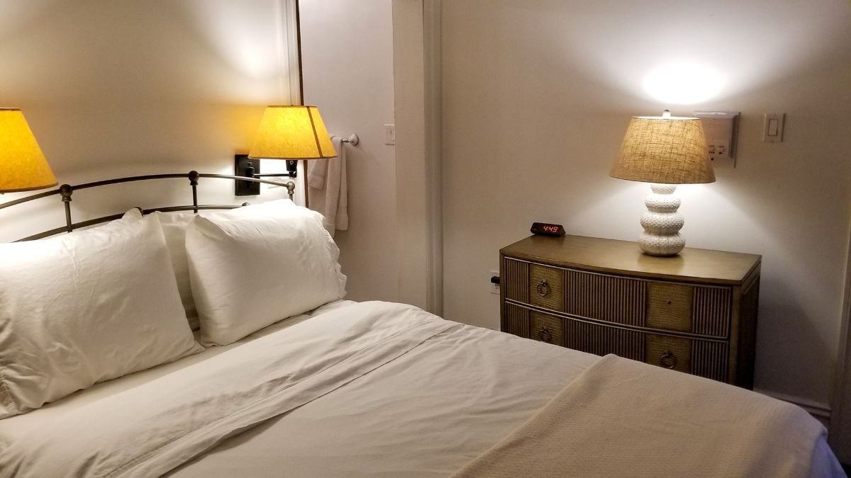 a bedroom with a bed , dresser , lamp and mirror .