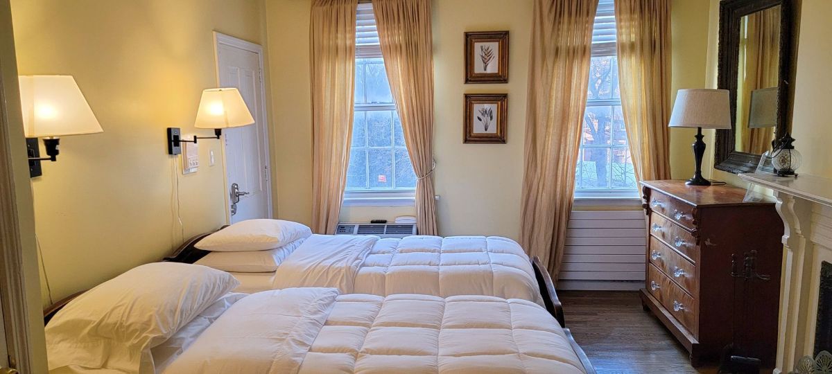 a bedroom with two beds , a dresser , and a fireplace .