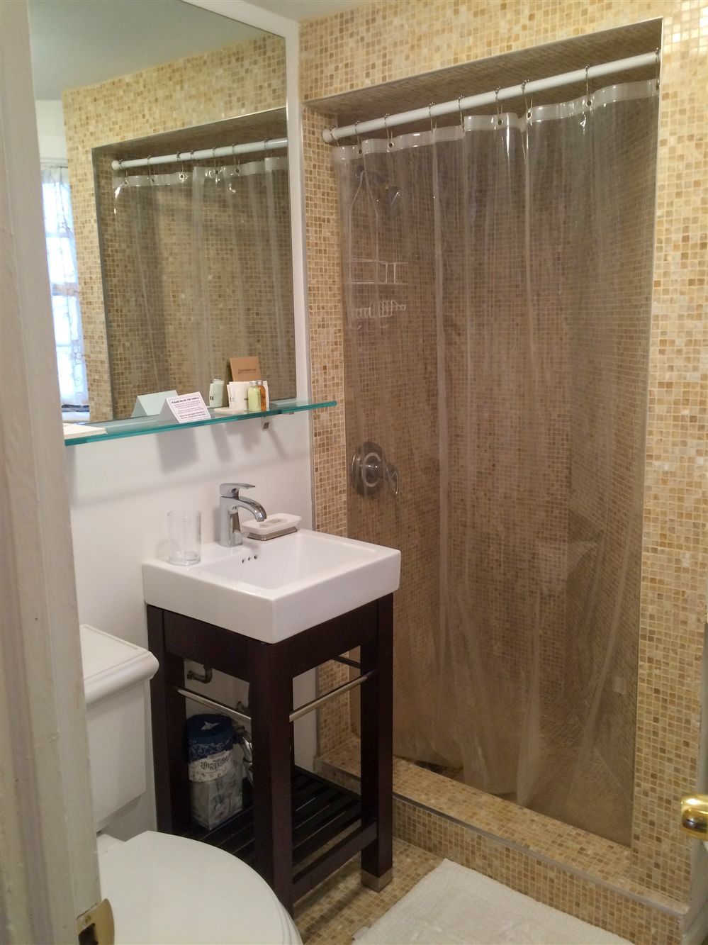 a bathroom with a sink , toilet , shower and mirror .