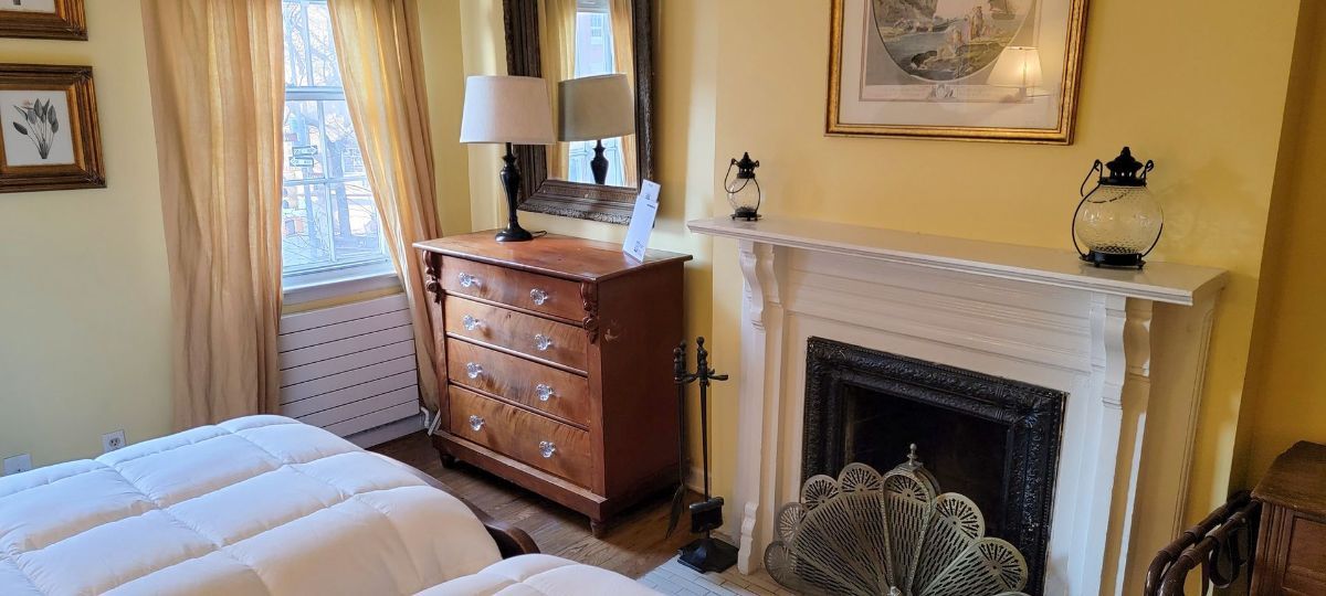 a bedroom with two beds , a dresser and a fireplace .