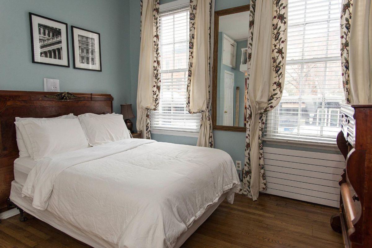a bedroom with a bed , dresser , mirror and window .