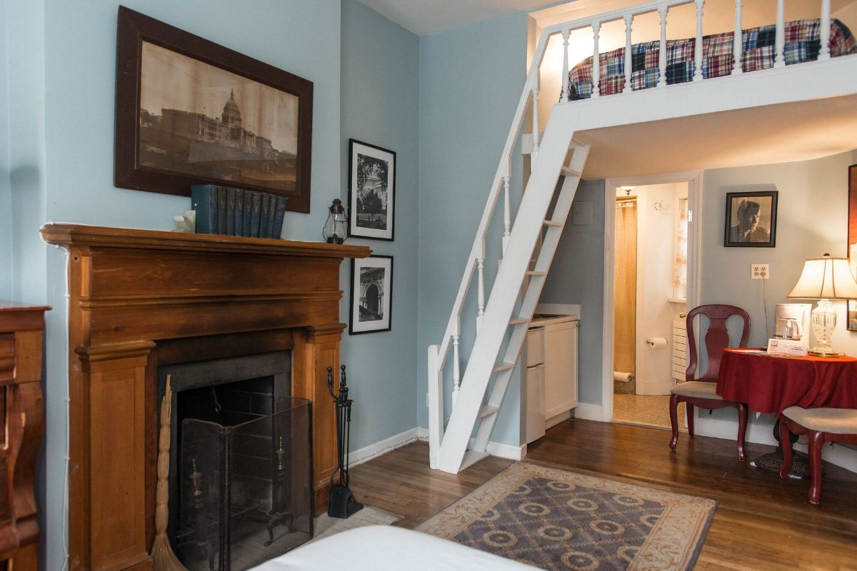 a living room with a fireplace and stairs leading to a loft .