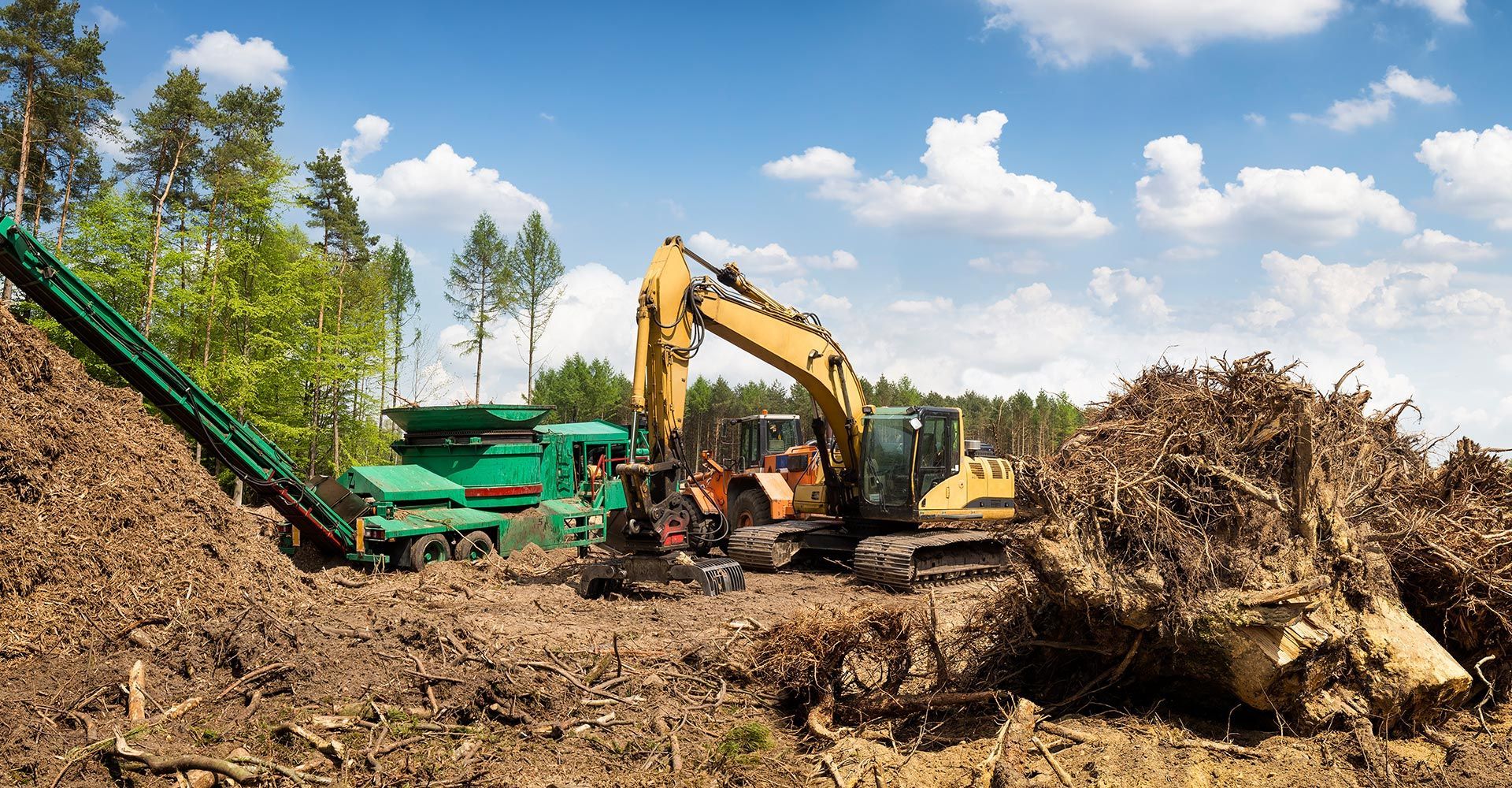 A large pile of wood chips is being processed by a machine. A large pile of wood chips is being processed by a machine.