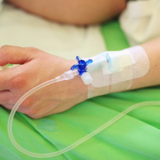 A person is laying on a bed with an iv in their arm.