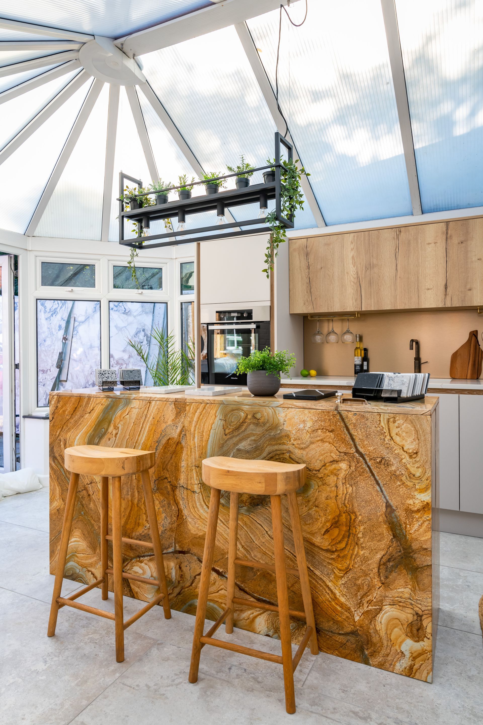 A kitchen with a marble counter top and wooden stools.