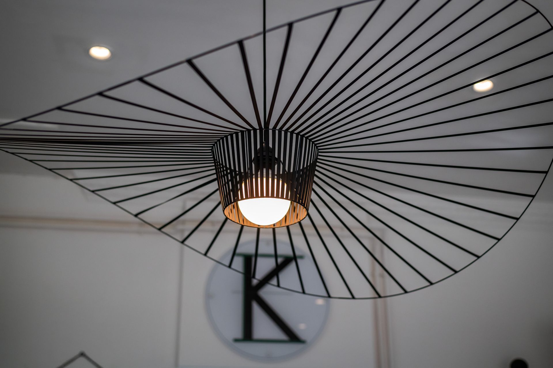 A light hanging from the ceiling with the letter k in the background