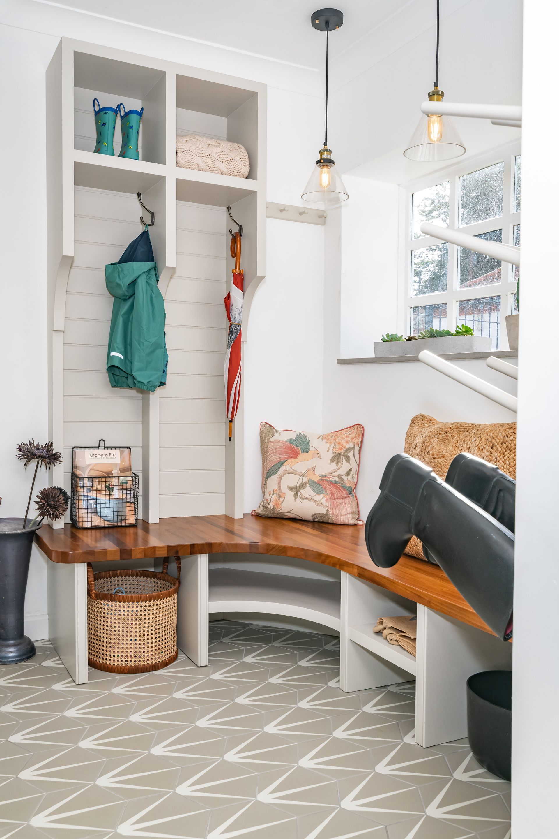 A mud room with a bench , shelves , and a window.