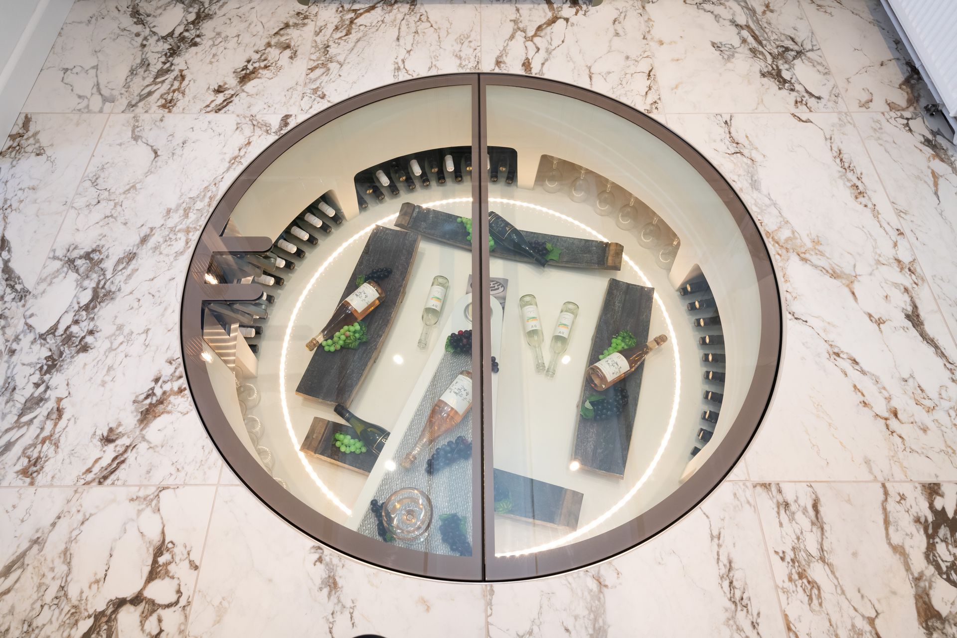 A round wine cellar with a glass door and a marble floor.