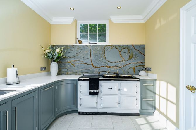 A kitchen with a stove and sink and a vase of flowers on the counter.