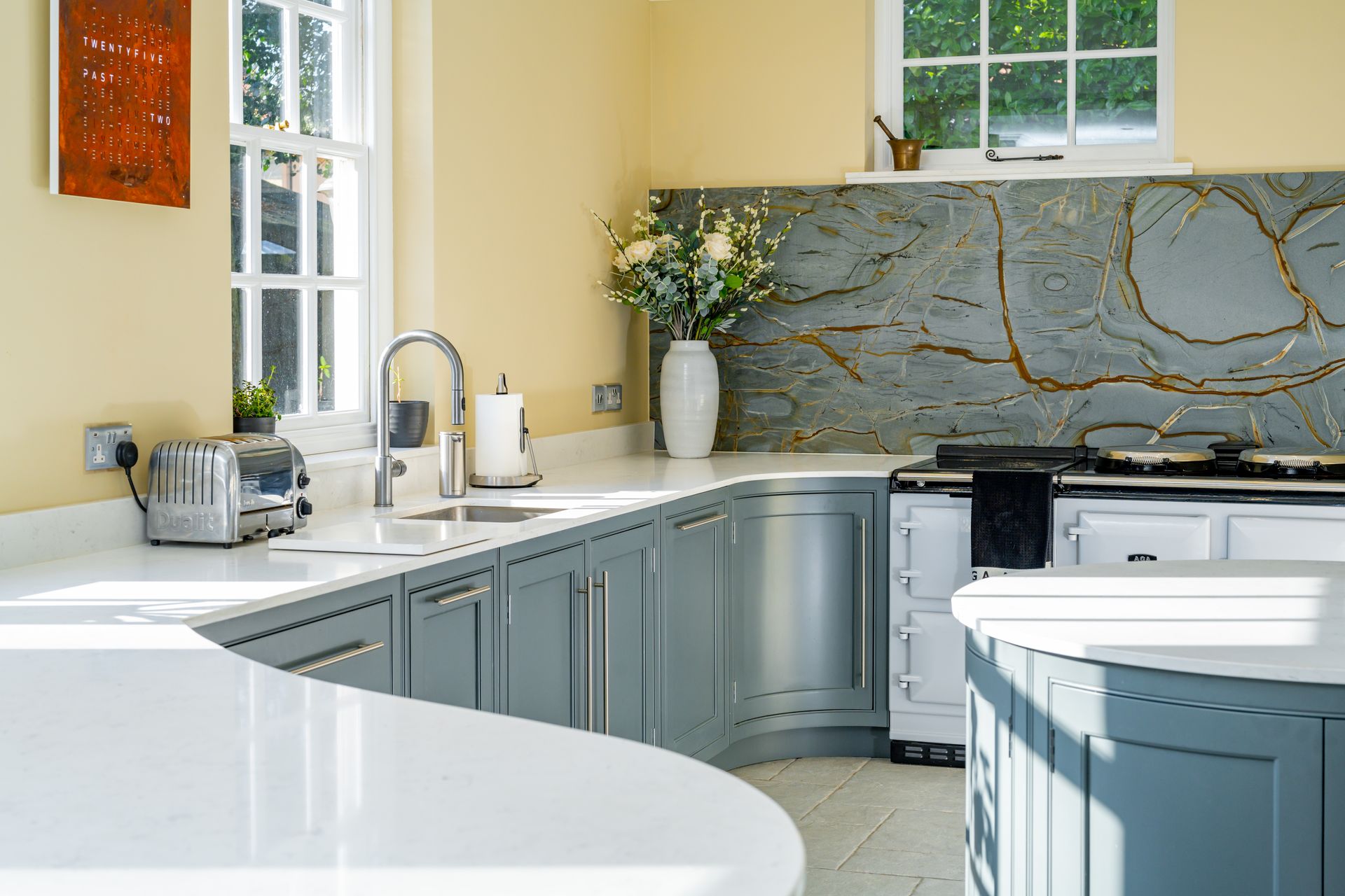 A kitchen with a large island and wicker bar stools.