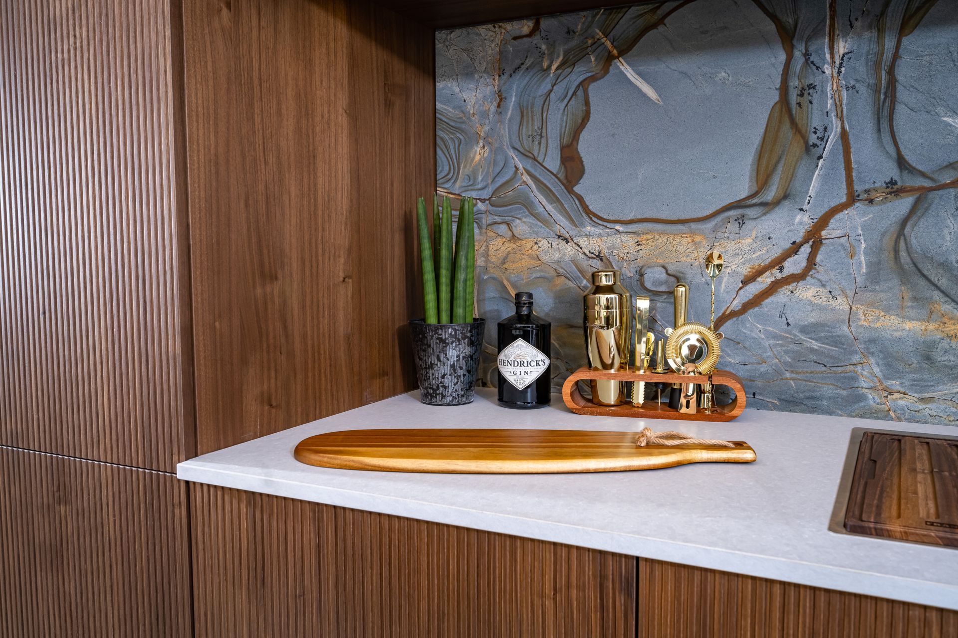 A wooden cutting board is sitting on a counter next to a bottle of gin.