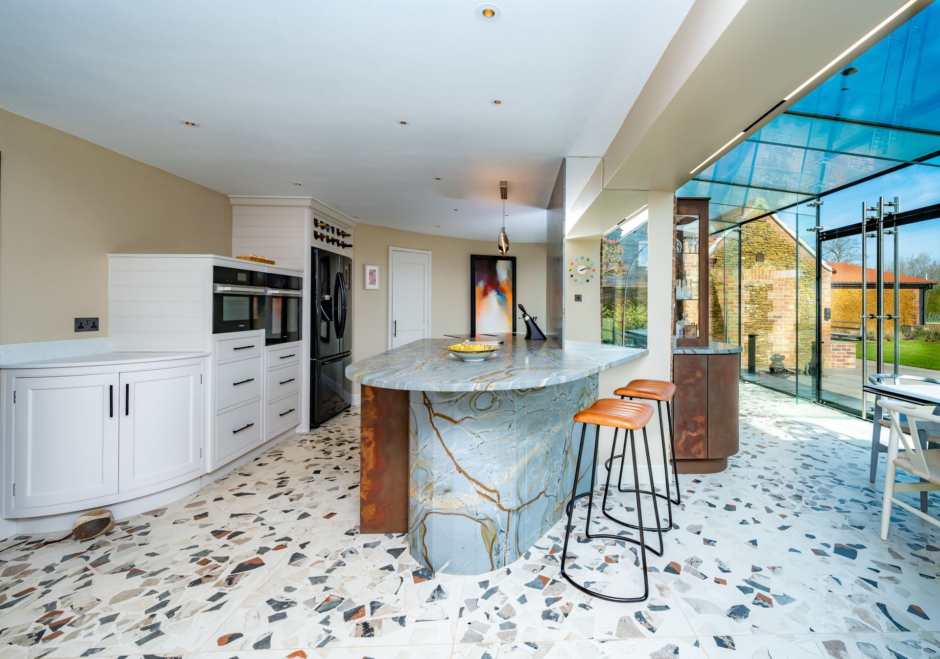 A kitchen with a large island and stools in it.