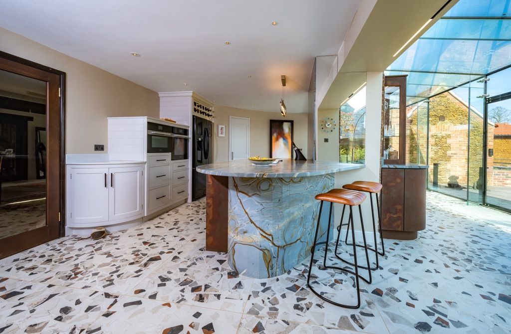 A kitchen with a large island and stools in it.