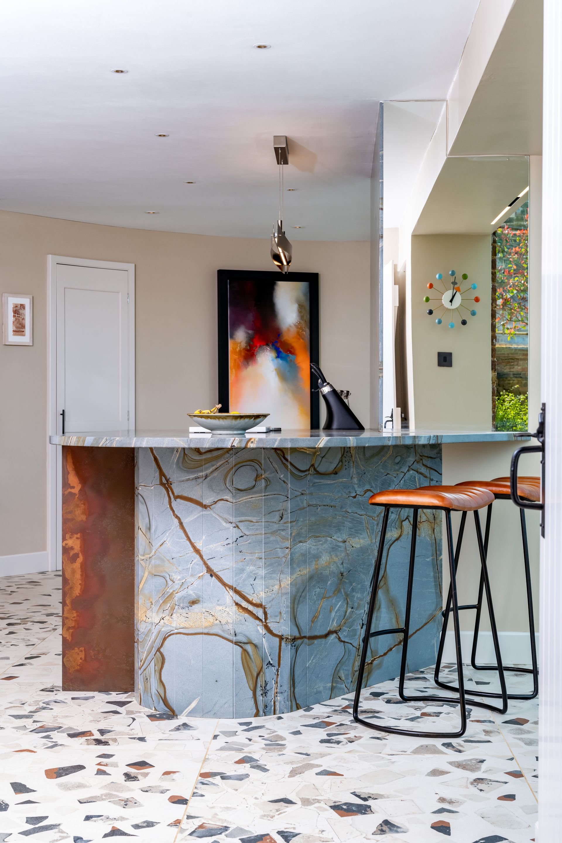 A kitchen with a marble counter top and stools.