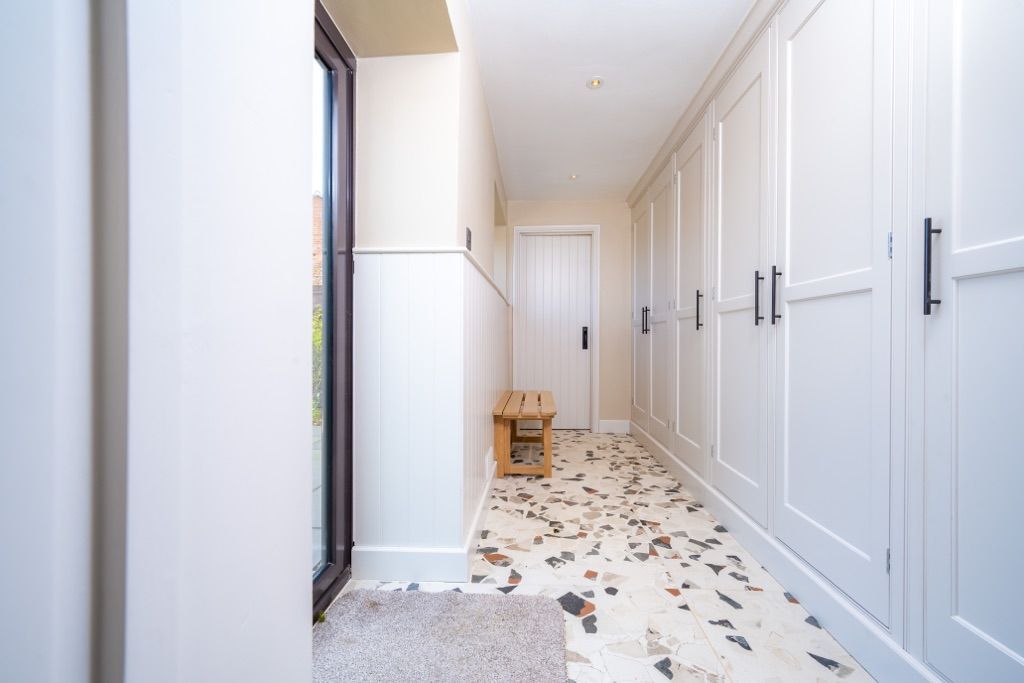 A long hallway with white cabinets and a marble floor.