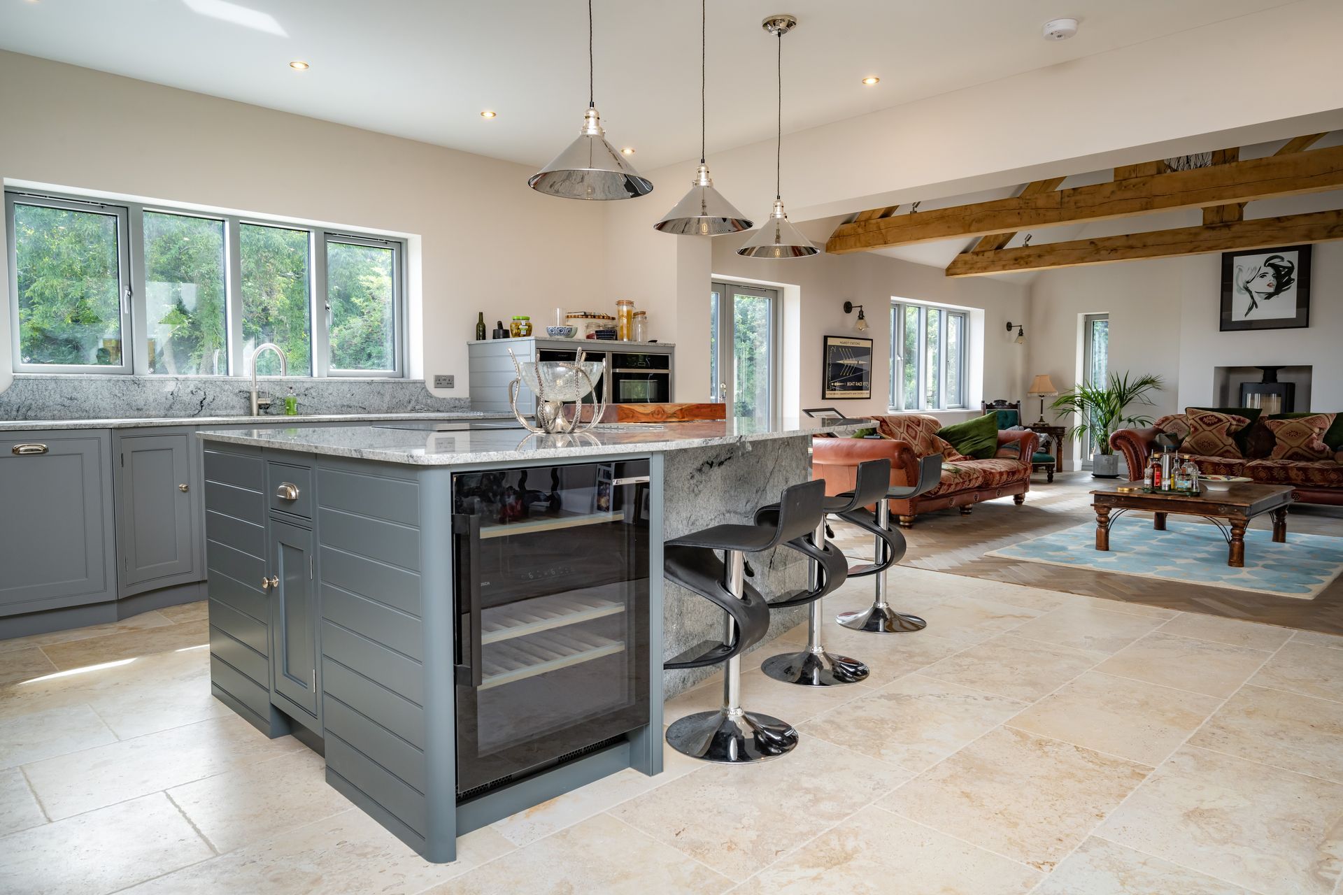A kitchen with a large island and stools in a living room.