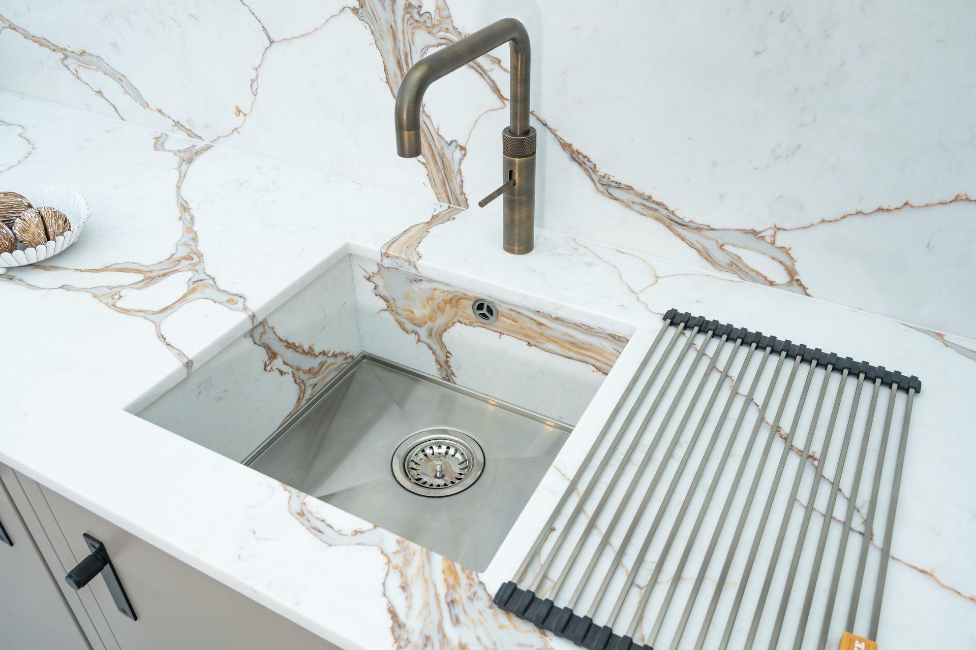 A kitchen sink with a stainless steel rack and a faucet.