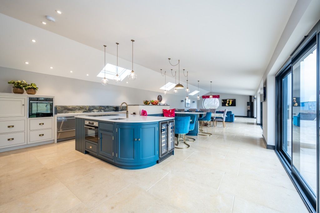 A large kitchen with blue cabinets and sliding glass doors.