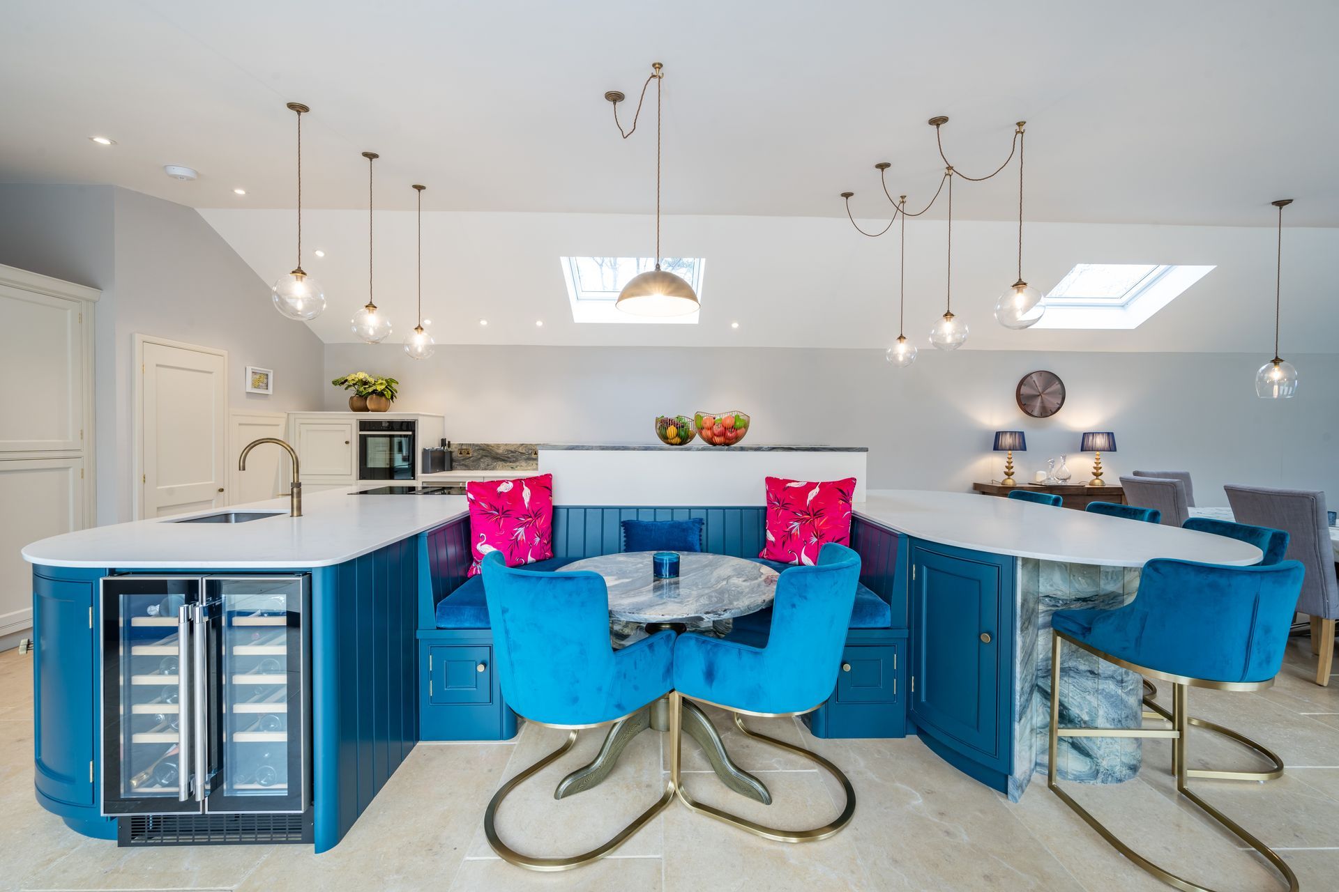 A kitchen with blue cabinets , blue chairs , a table and a refrigerator.