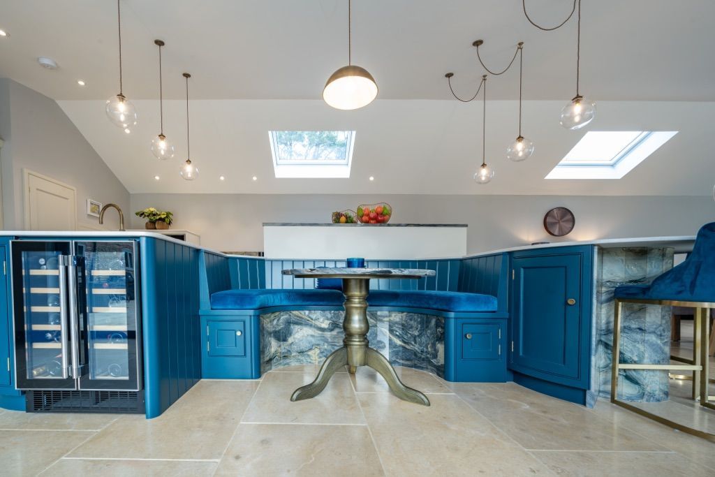 A kitchen with blue cabinets , a table and benches.