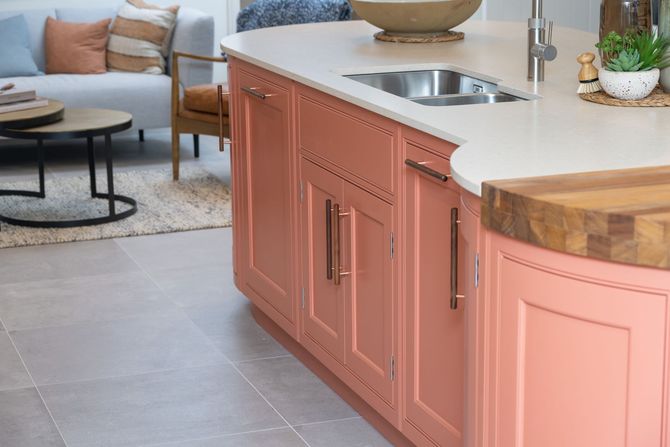 A kitchen with pink cabinets and a sink in a living room.