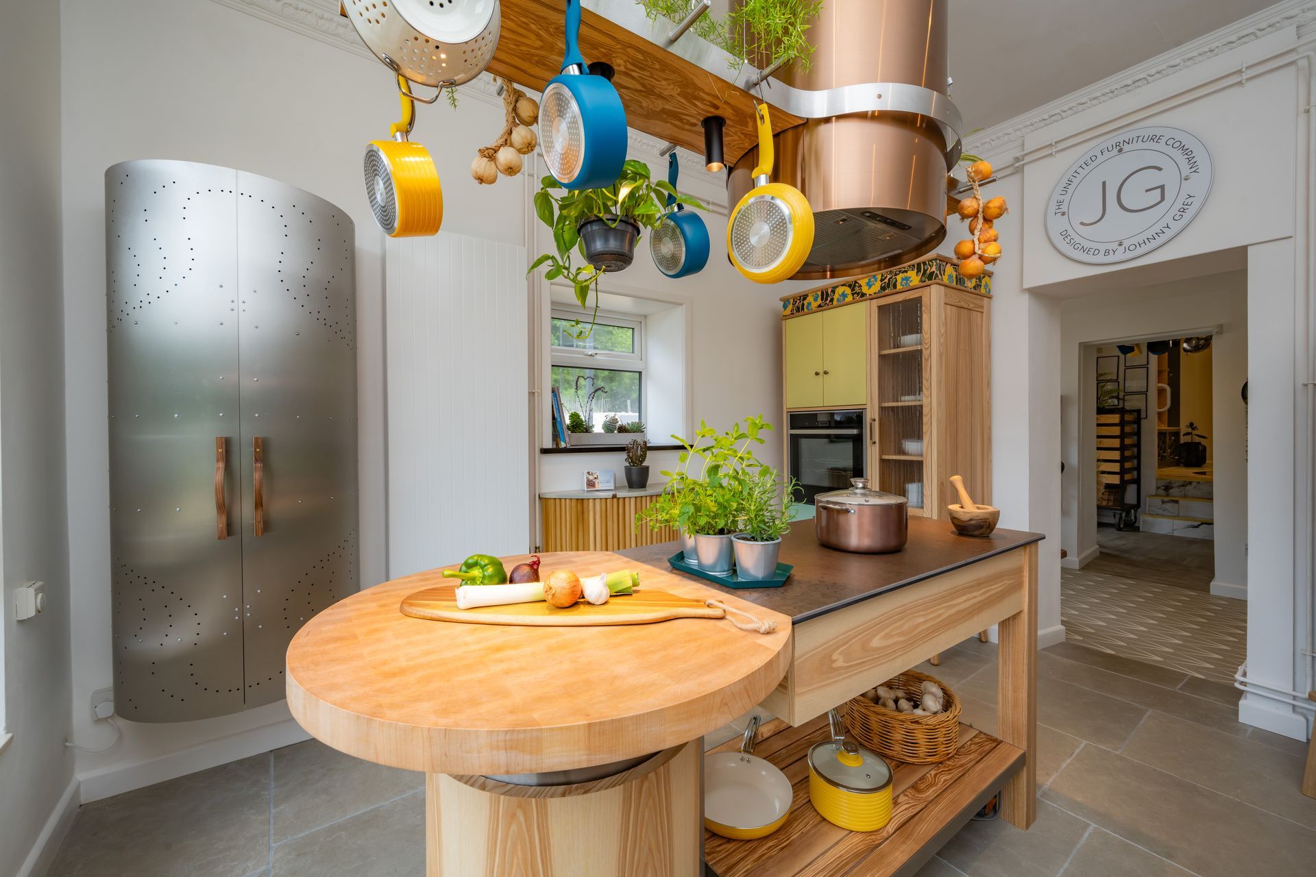 A kitchen with a wooden table and pots and pans hanging from the ceiling.