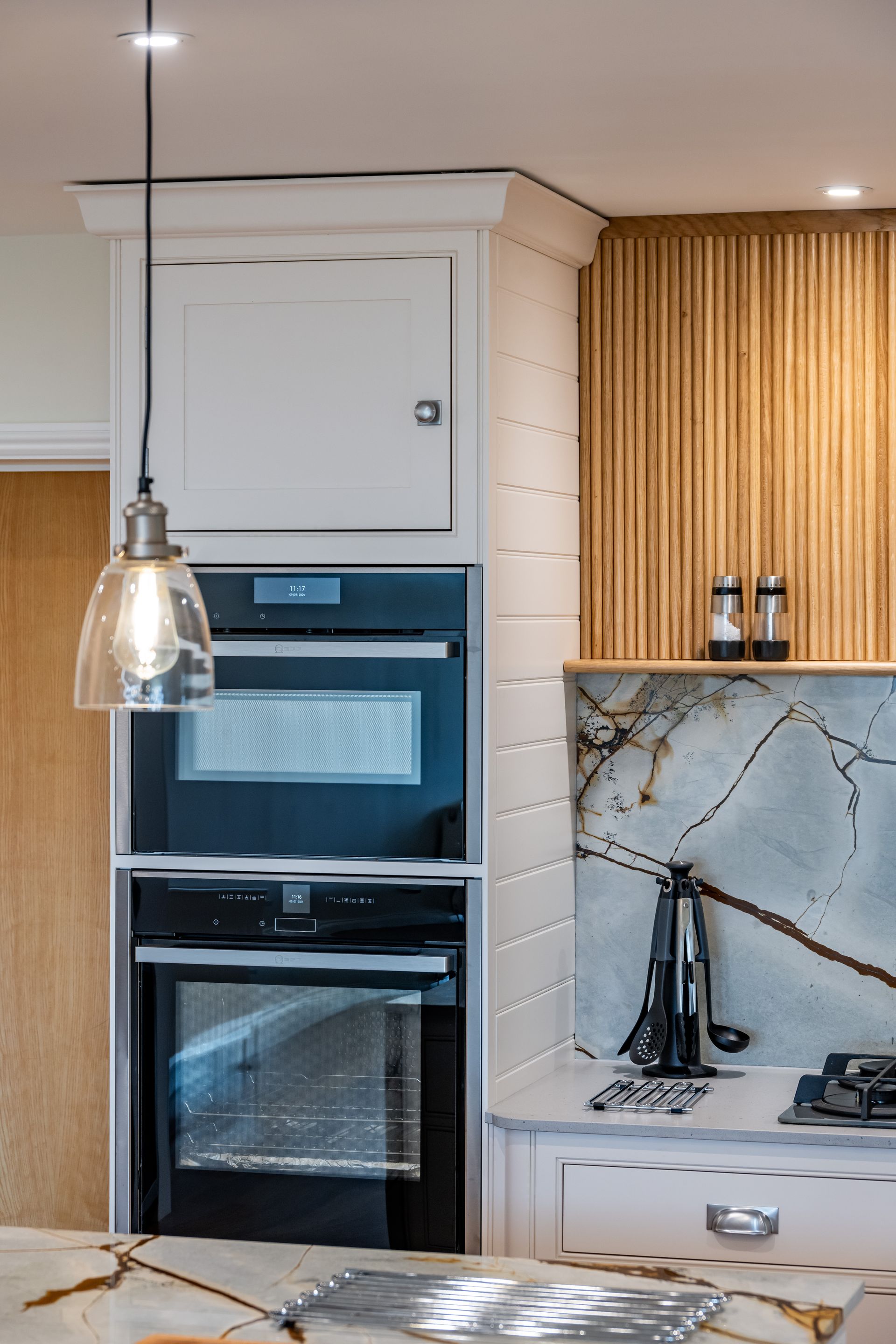 A kitchen with a black oven and a light hanging from the ceiling.