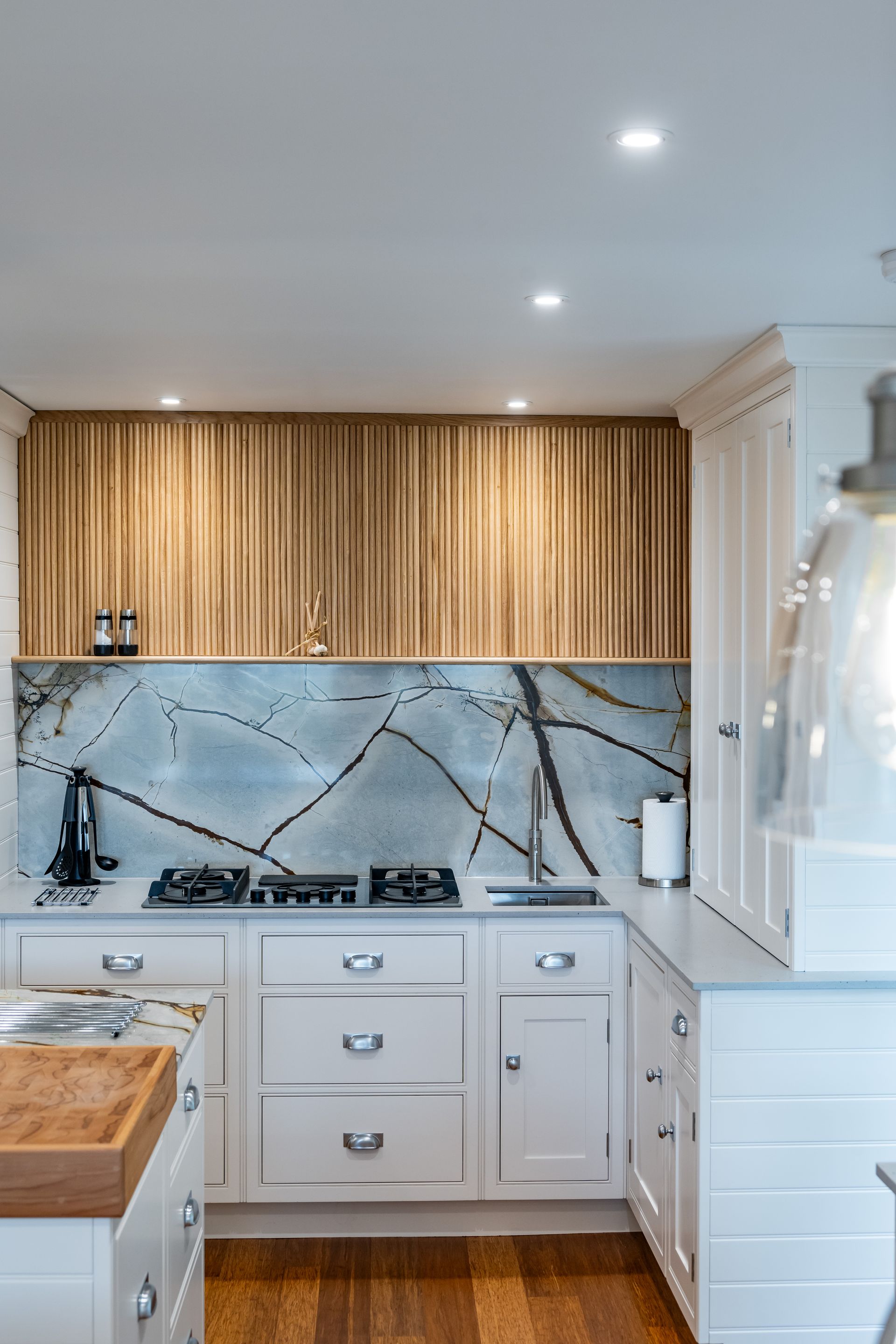 A kitchen with white cabinets and wooden cabinets and a stove top oven.