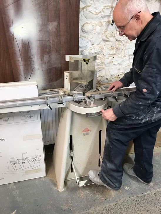 A man is using a machine to cut a piece of wood.