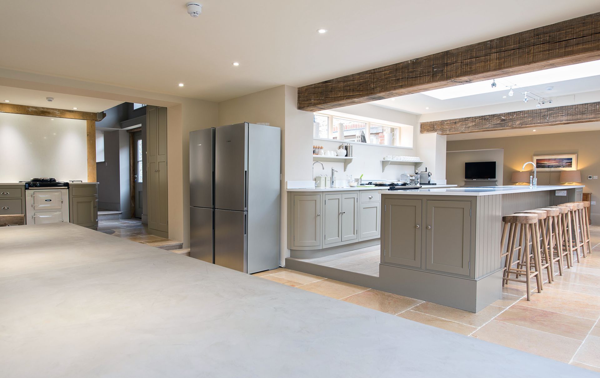 A kitchen with a large island and wicker bar stools.