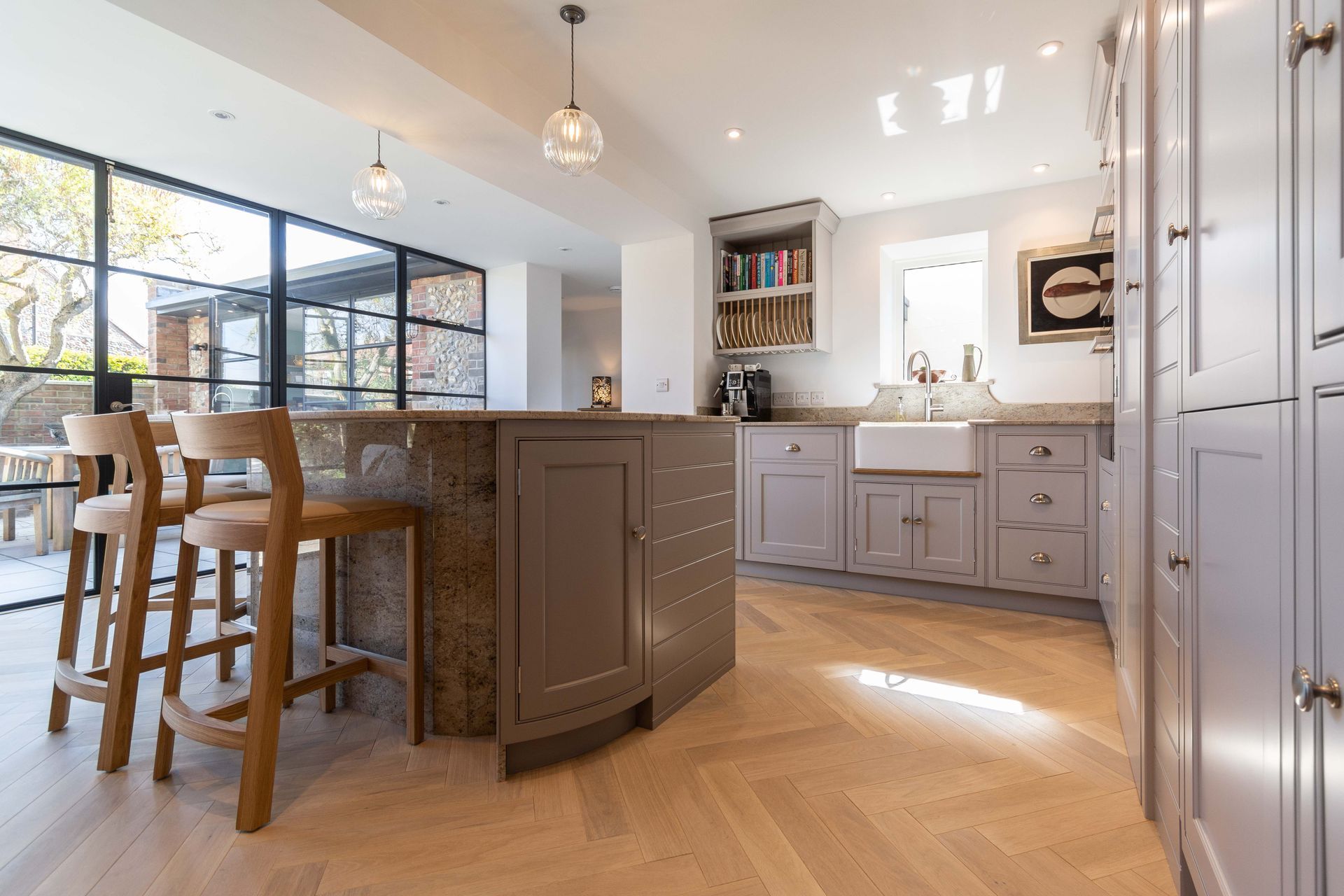 A kitchen with a large island and stools in it.