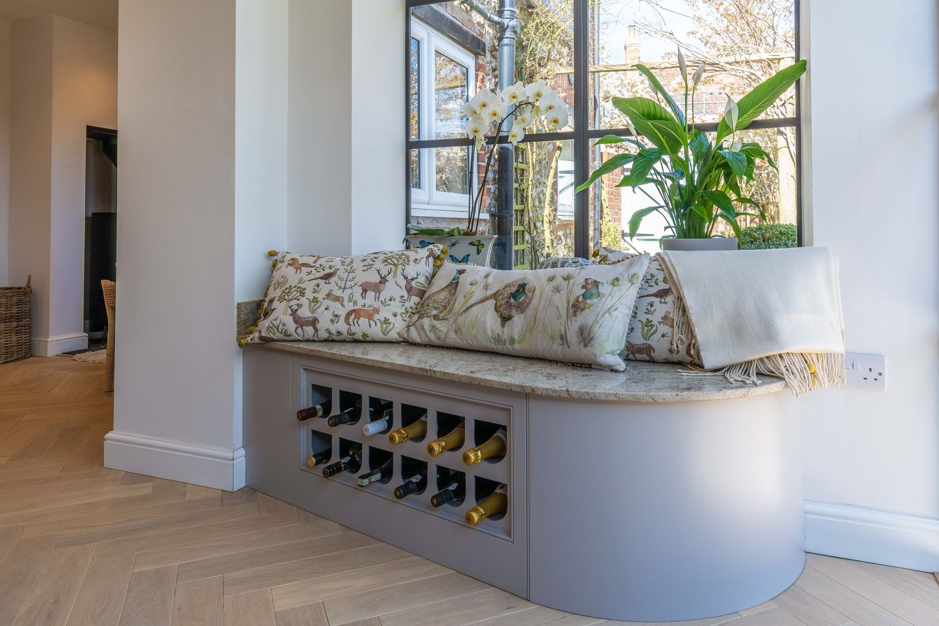 A window seat with a wine rack underneath it in a living room.