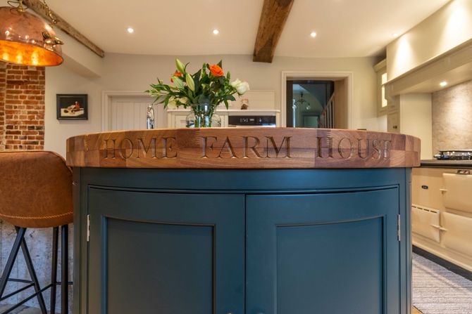 A kitchen island with a wooden cutting board on top of it.