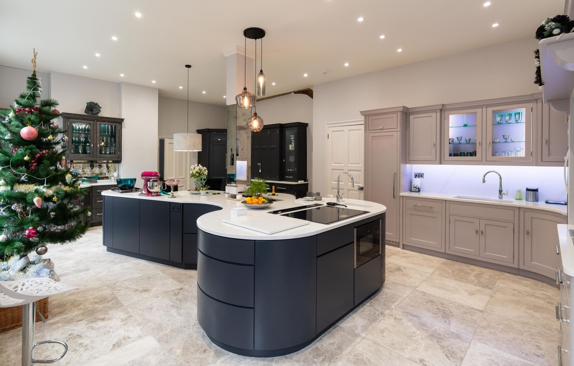 A large kitchen with a christmas tree in the background.
