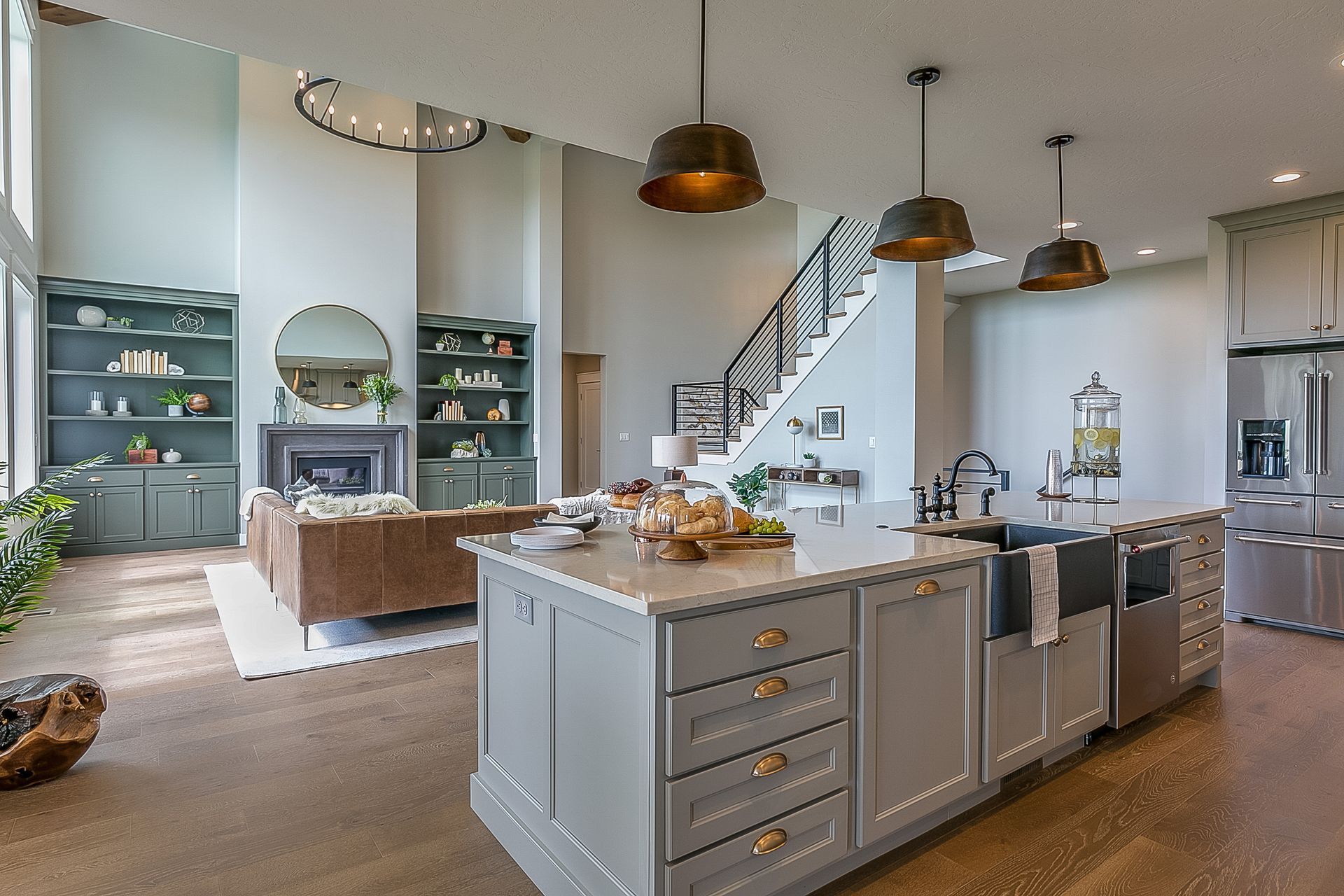 Spacious kitchen with island, adjacent living room, staircase, and open shelving.