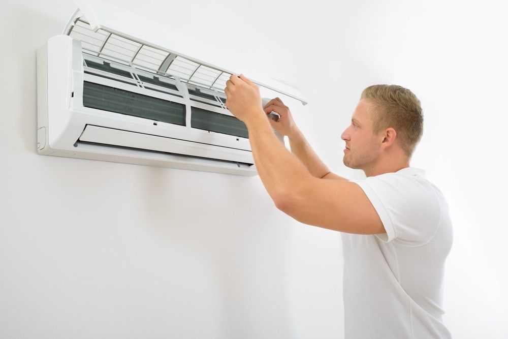 A Man Cleaning an Air Conditioning Unit — Careda Air in Gerringong, NSW