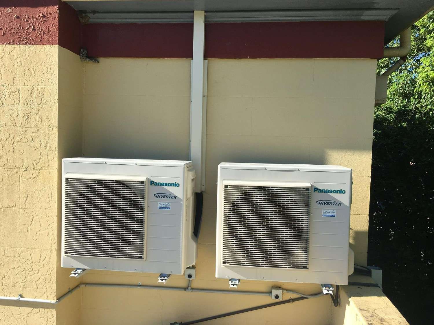 Two Panasonic Air Conditioning Units Mounted on a Beige Exterior Wall — Careda Air in Saint Georges Basin, NSW